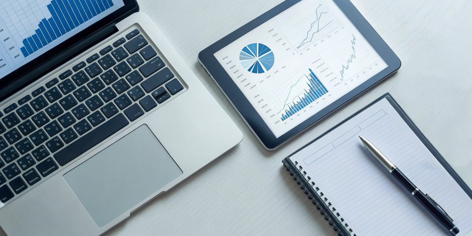 A laptop and tablet displaying charts for automated newsletter reports for clients.